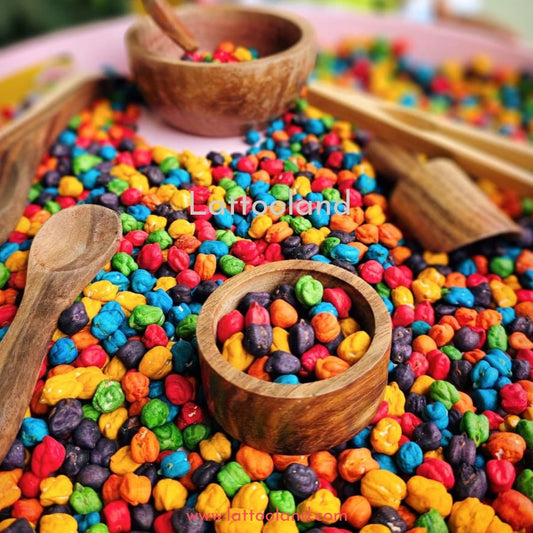 Chickpeas dyed in a range of vibrant colors like pink, purple, orange, and teal, arranged in a sensory bin. The bright hues and smooth textures provide a stimulating and interactive sensory play experience for children.
